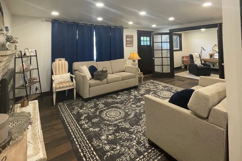 The lounge, with sofas, a patterned rug and the treatment room through glass doors at the back